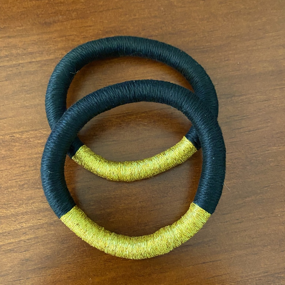 Two gold and black threaded bracelets.